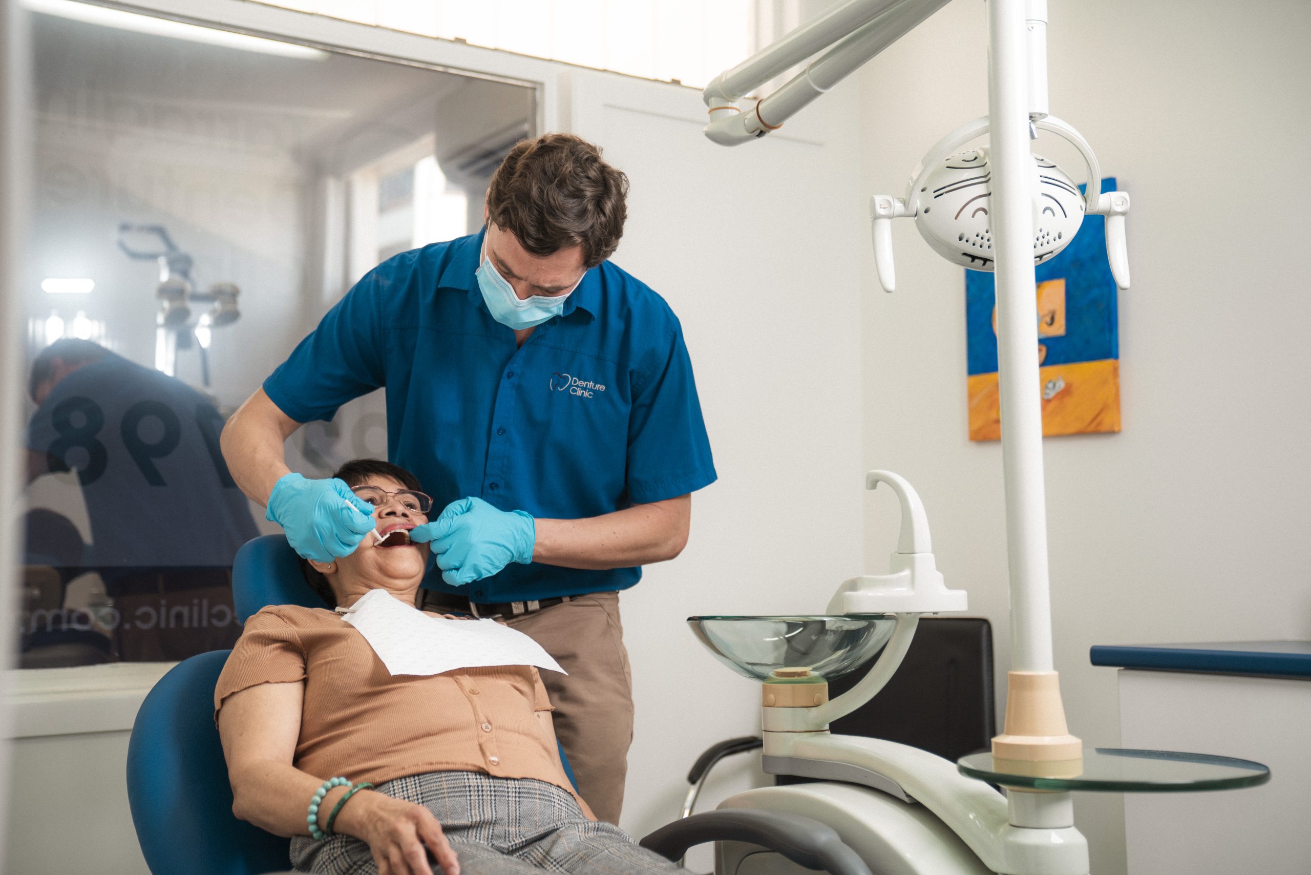 A dental prosthetist adjusting a patient's dentures