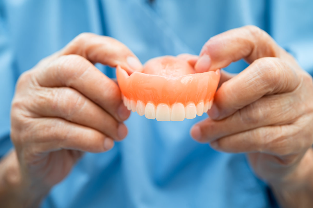 Asian elderly woman patient holding to use denture, healthy stro Getting Used to a New Denture